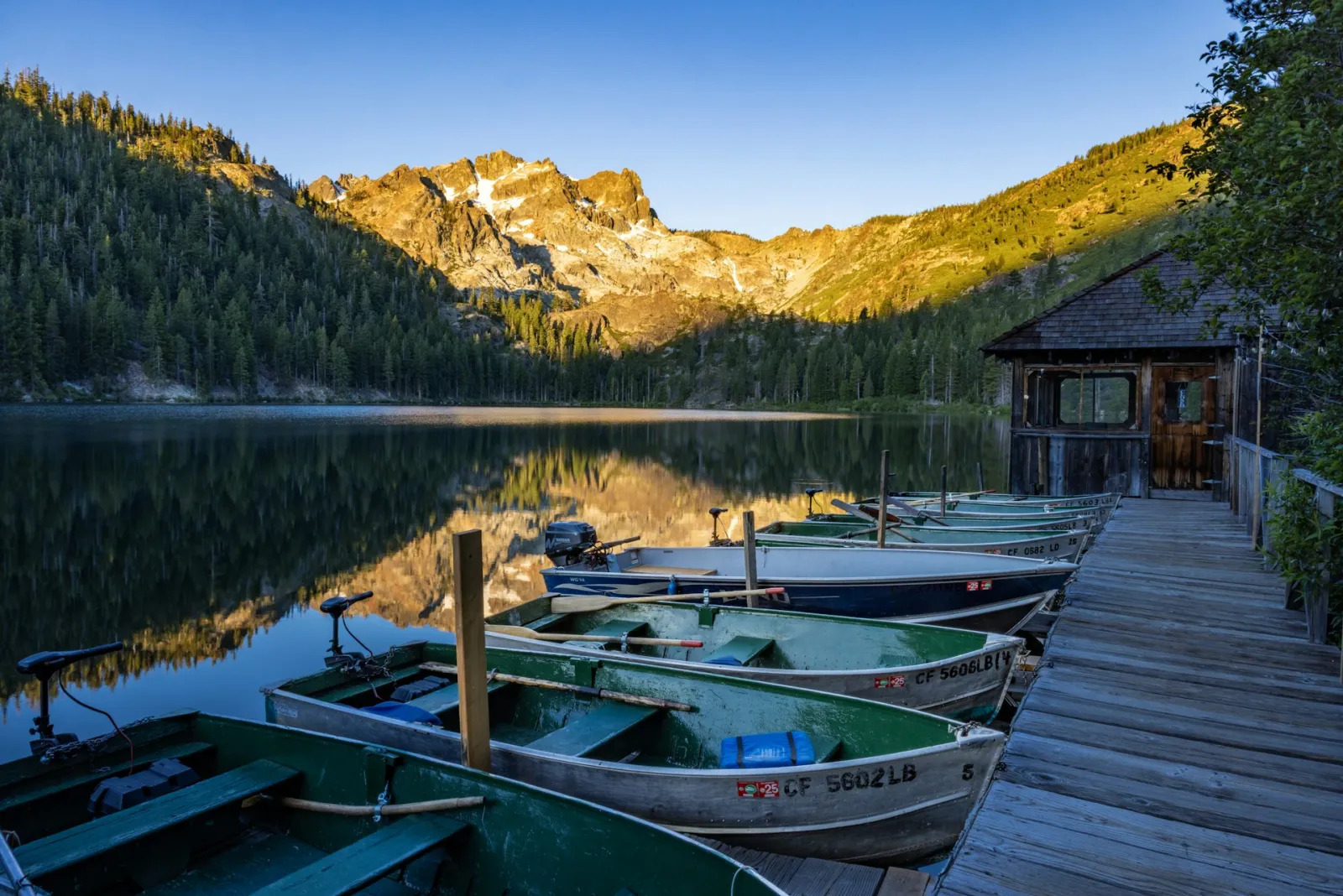 Boats docked on a scenic Lake Como at sunrise with mountains in the background