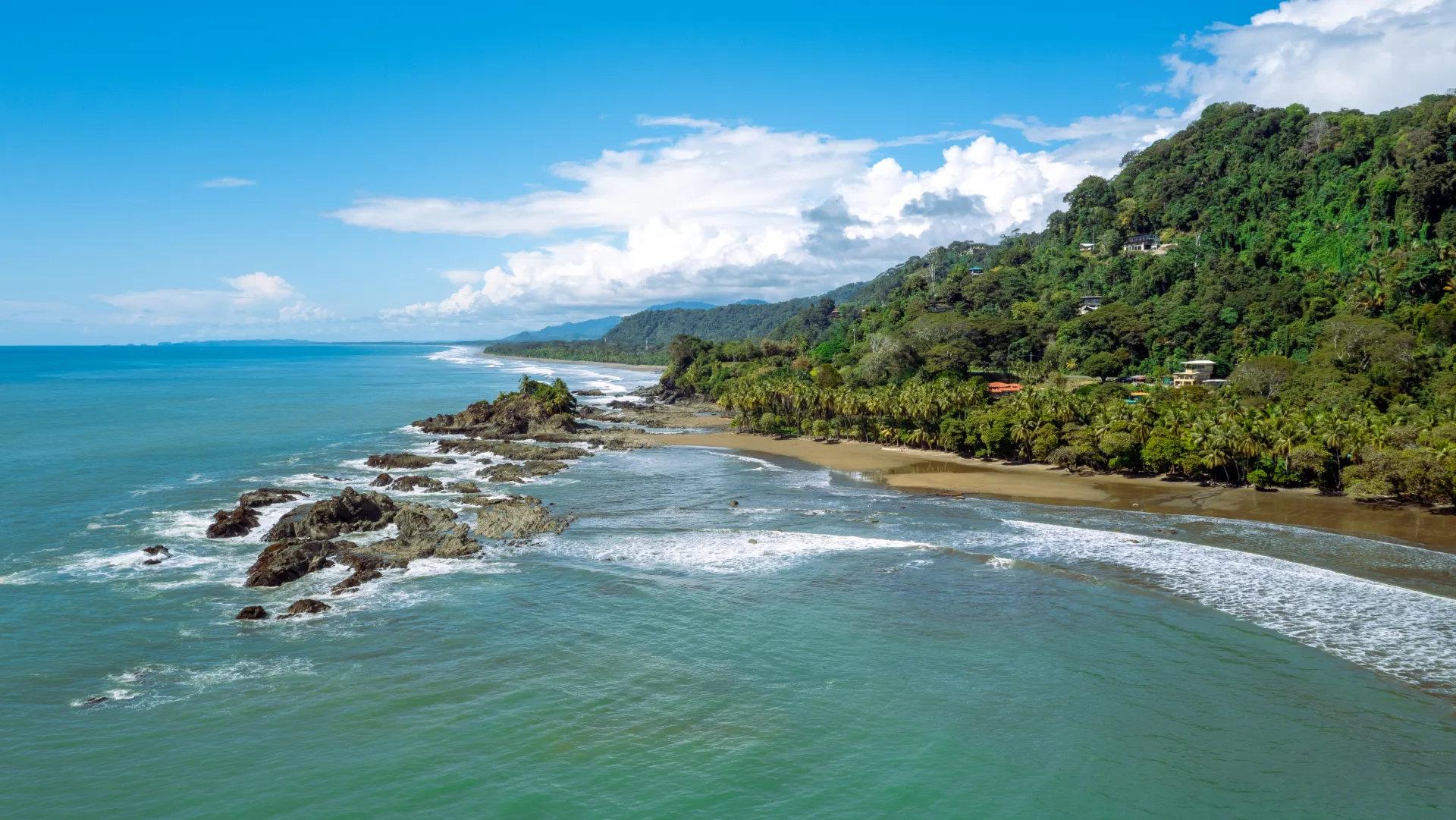 Tropical coastline of Costa Rica with lush green hills meeting the Pacific Ocean