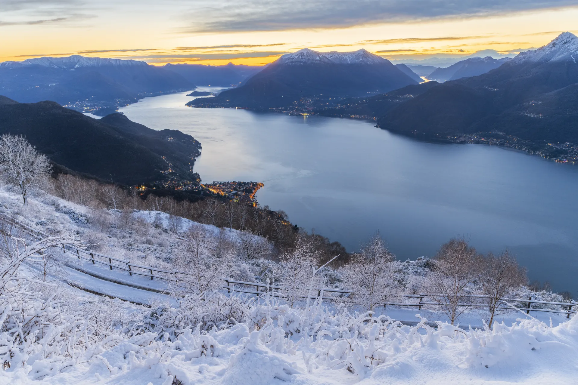 Lake Como and its mountains at sunset, seen from a snowy hillside in winter